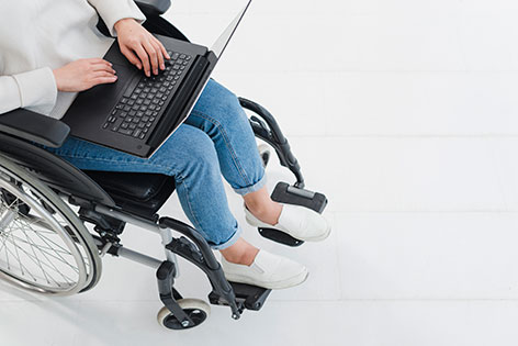 Woman typing on laptop sitting on wheelchair